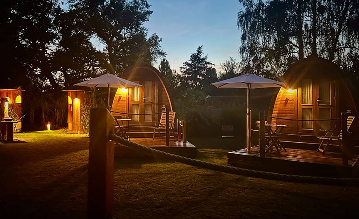 Cabanes en bois illuminées dans le Jardin des roseaux, le soir