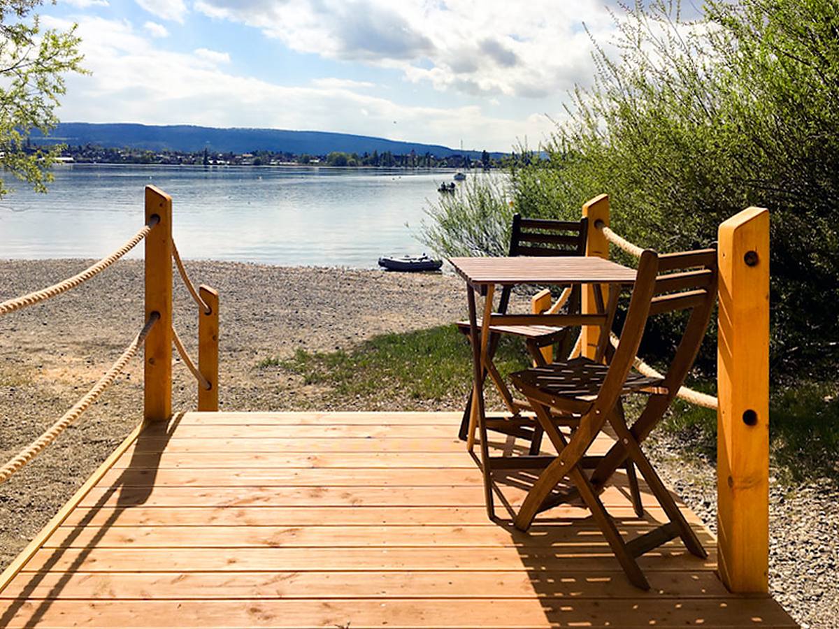 Terrasse d'une cabane au bord du lac, sur la plage de galets